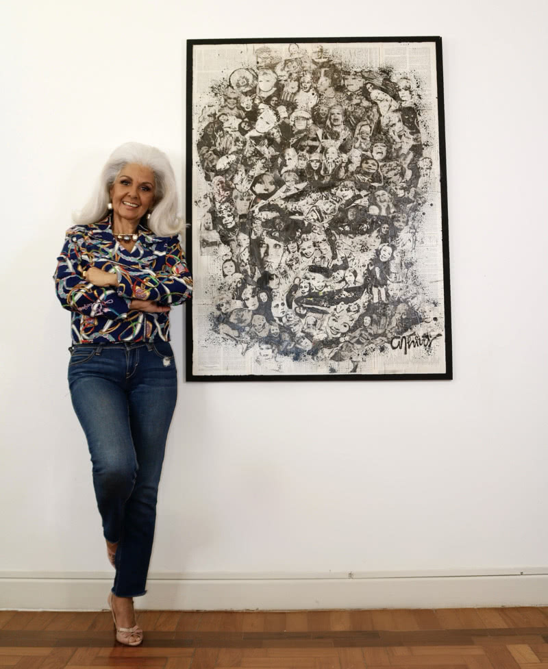 Lucy com a obra do artista plástico Anderson Thives que ilustra a capa do livro que ela escreveu sobre a tia avó (Foto: Aramis Freitas)